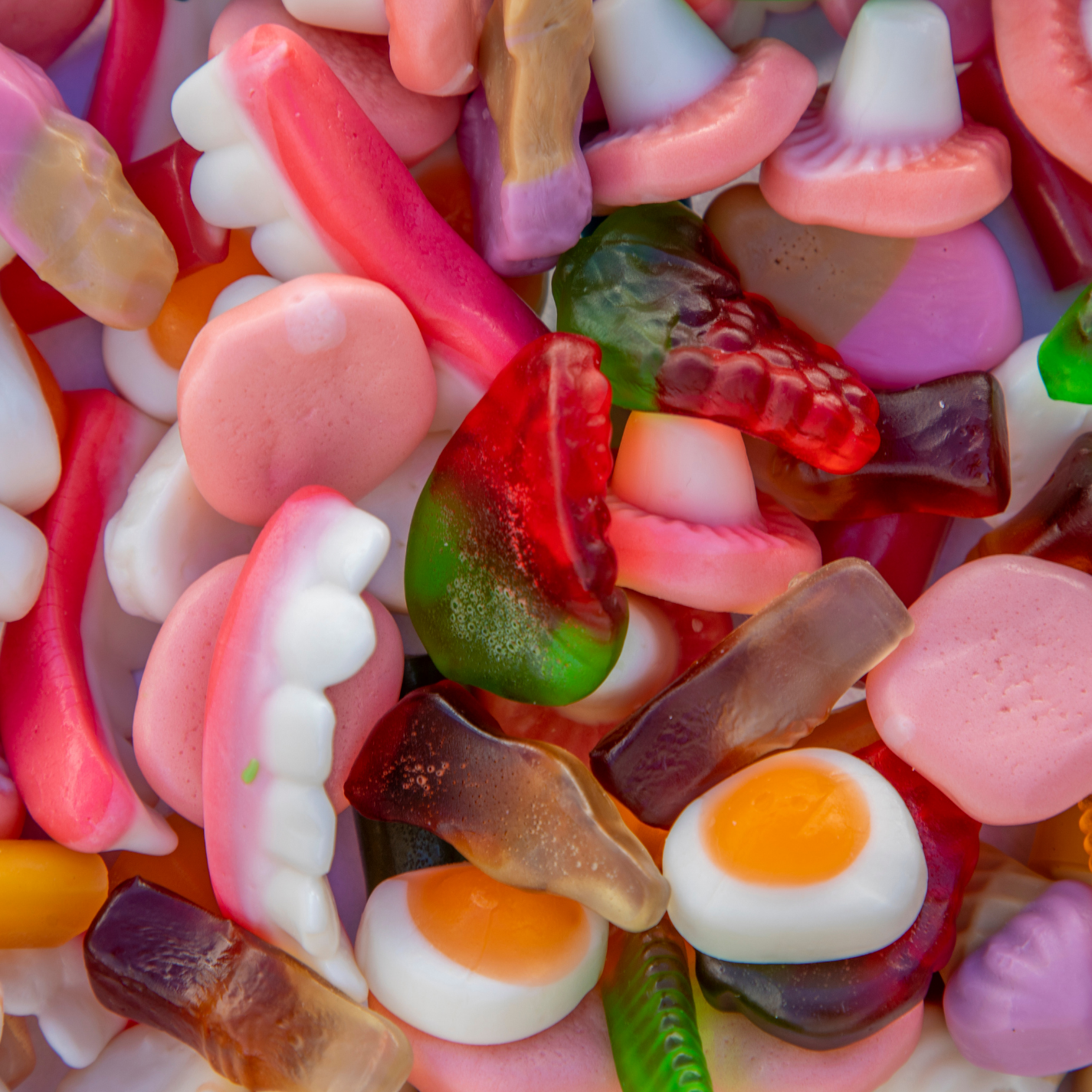 Glass jar filled with colourful loose gummy sweets including gummy bears, worms and rings - shop gummies by weight
